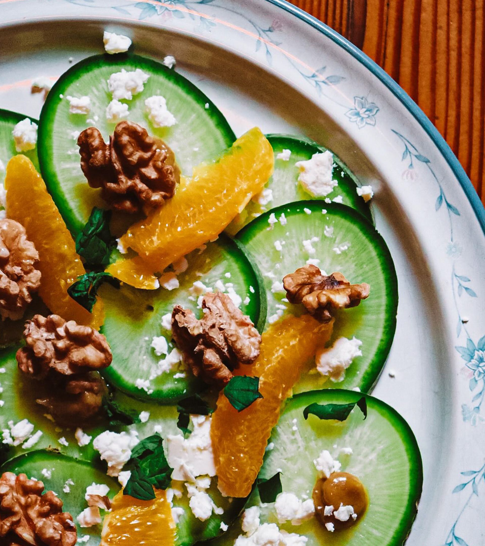 Forage plate: cucumber carpaccio with orange segments, walnuts, feta on vintage floral-rimmed plate