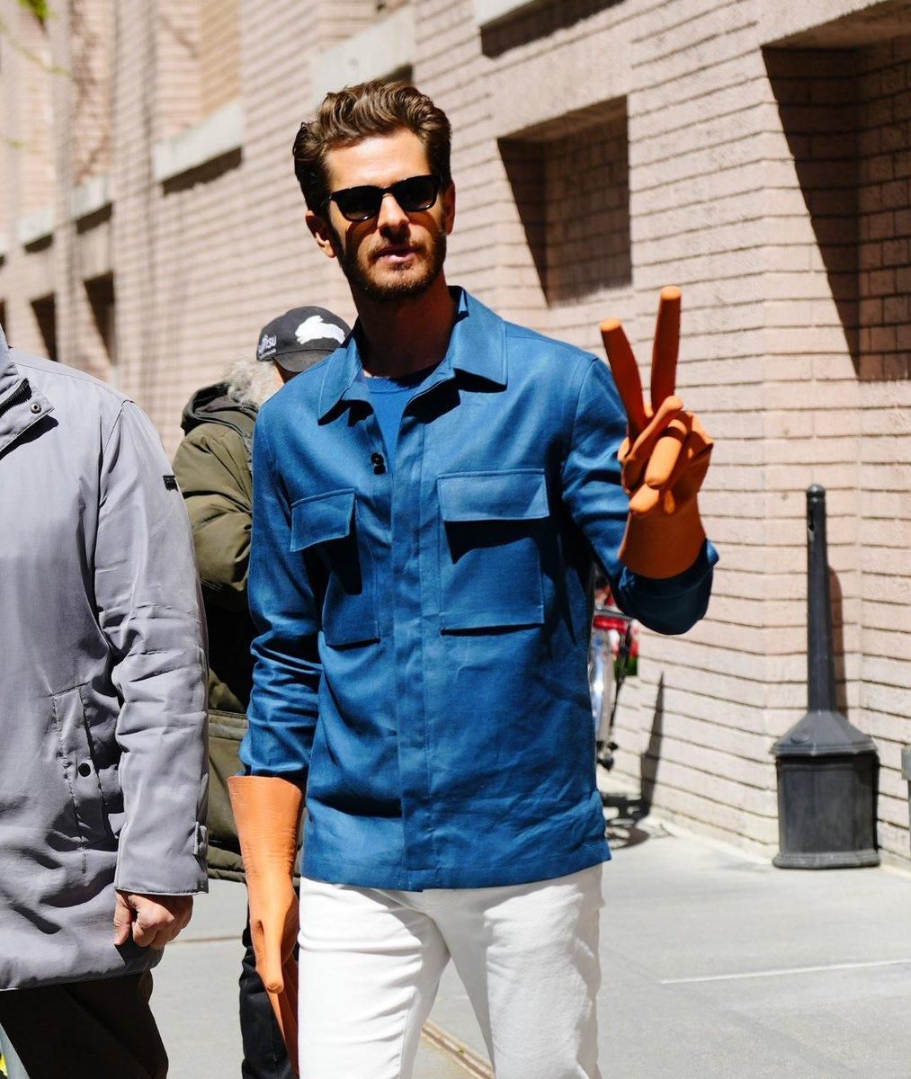 A24 Everything Everywhere All at Once; Andrew Garfield flashing peace sign with hot dog finger gloves on city street