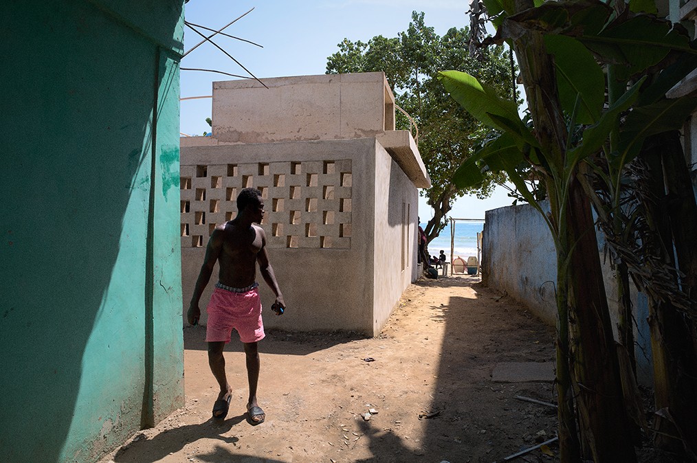 A figure stands between a green wall and a wall of concrete blocks