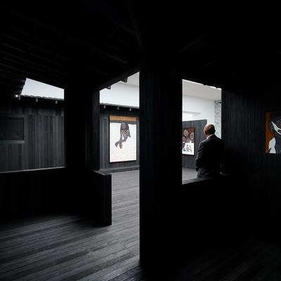 A digital render of a wall with print on it next to a wall with text on it. Two people stand next to these walls, while a third is framed by the entrance into a further room on the horizon.