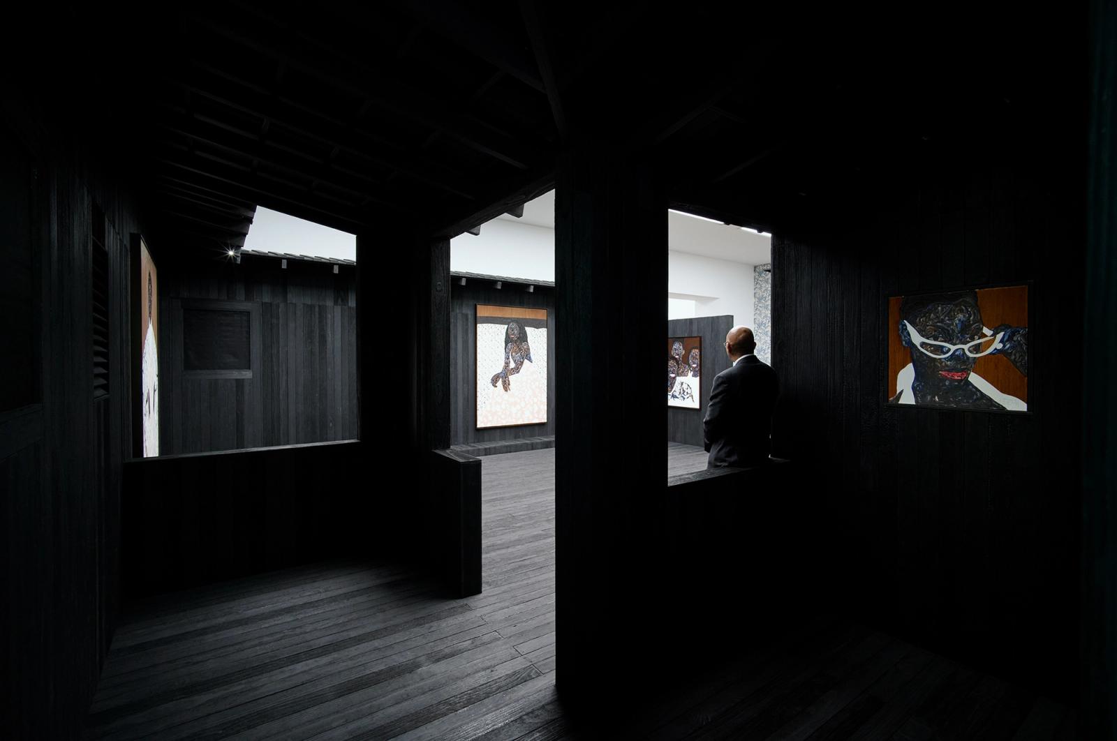 A digital render of a wall with print on it next to a wall with text on it. Two people stand next to these walls, while a third is framed by the entrance into a further room on the horizon.