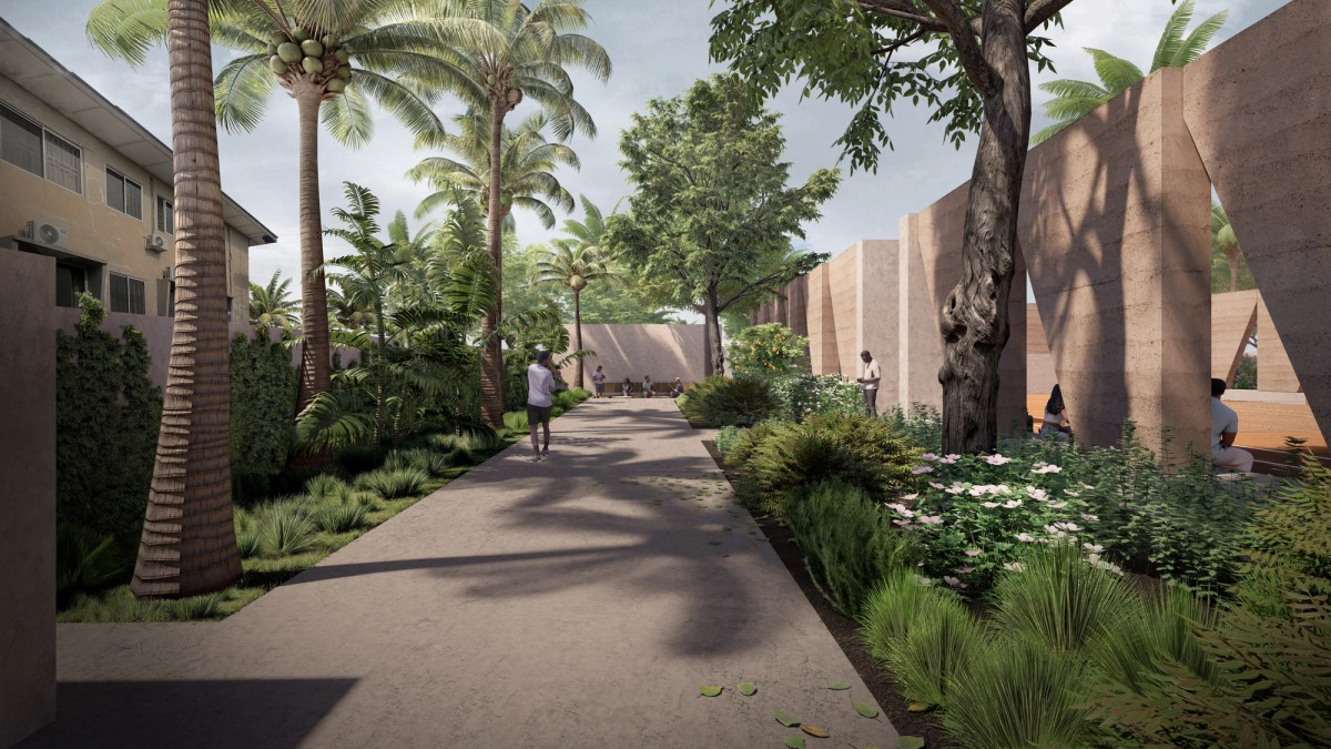 A landscaped pathway lined with palm trees, lush greenery, and flowering plants winds through a tranquil courtyard bordered by earthen-toned walls. People walk, sit, and enjoy the shaded, garden-like atmosphere, creating a peaceful, communal setting.