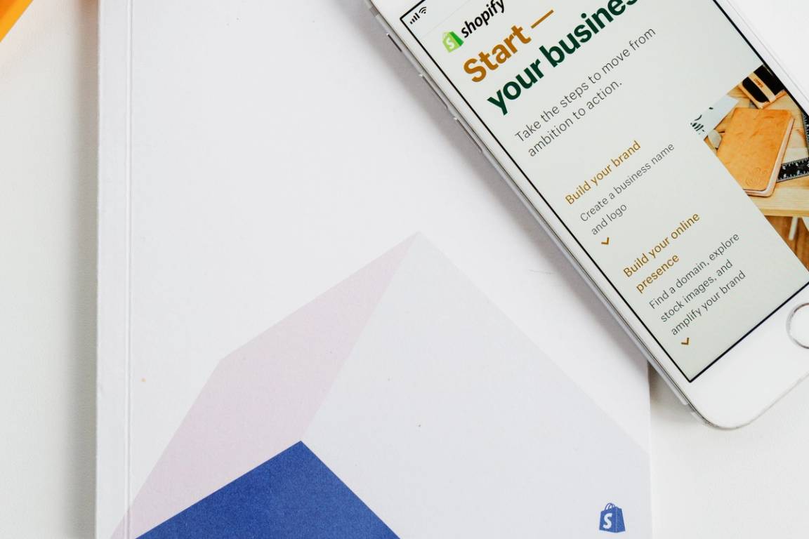 A photo of a phone open to shopify.com along with a printed Shopify book