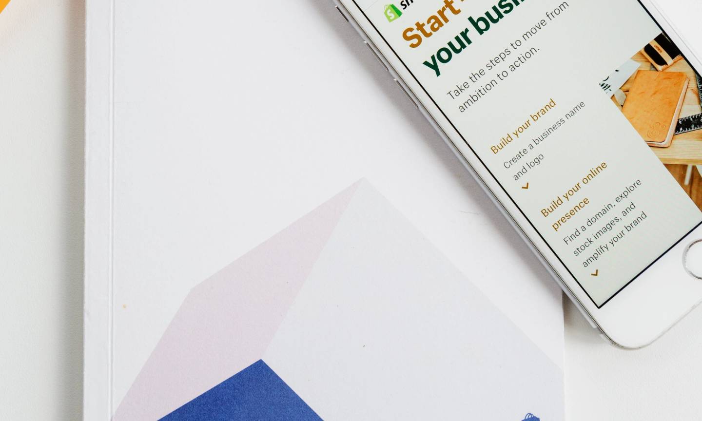 A photo of a phone open to shopify.com along with a printed Shopify book