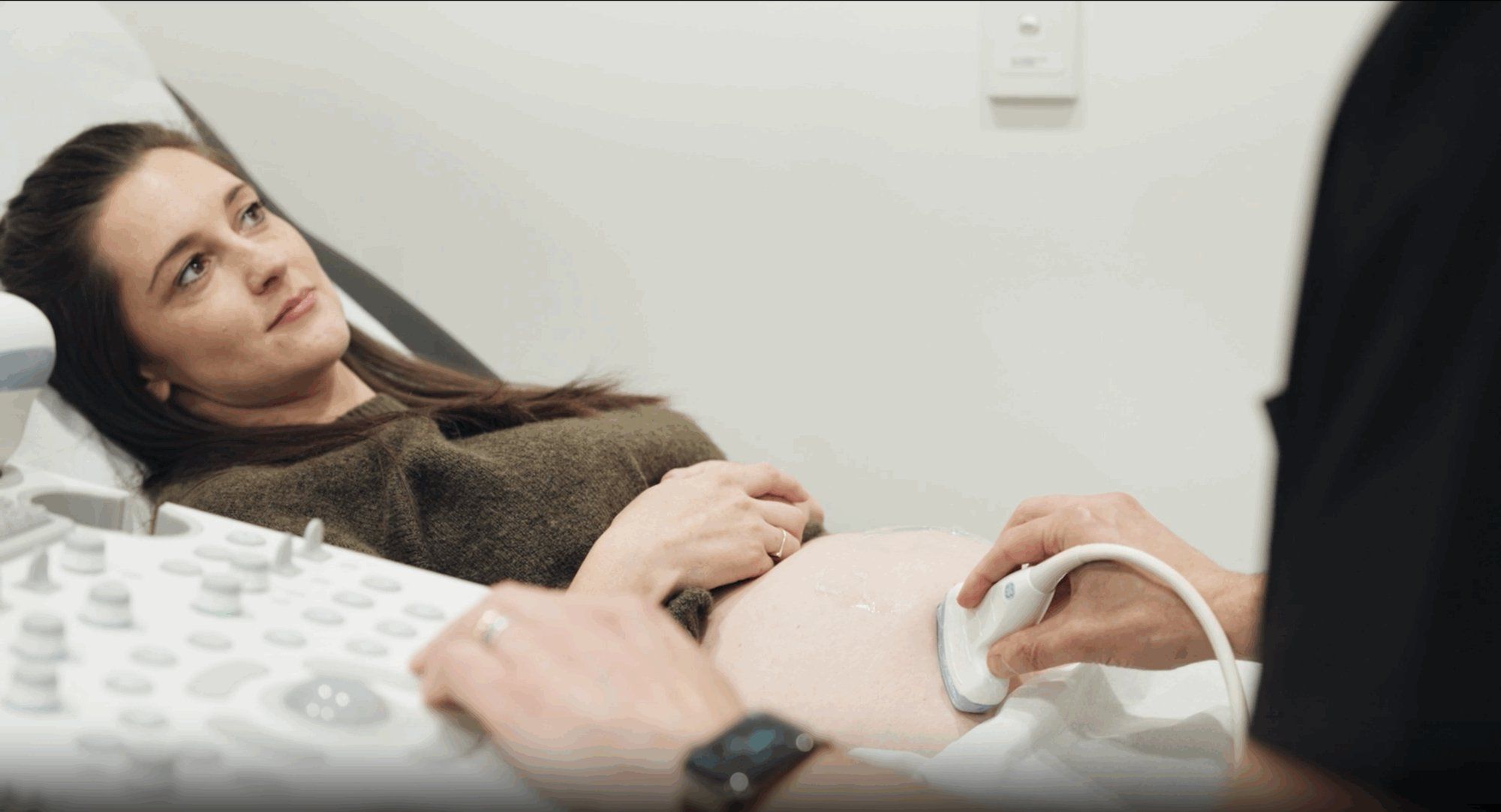 A pregnant woman at an antenatal appointment with her obstetrician in a light consulting room