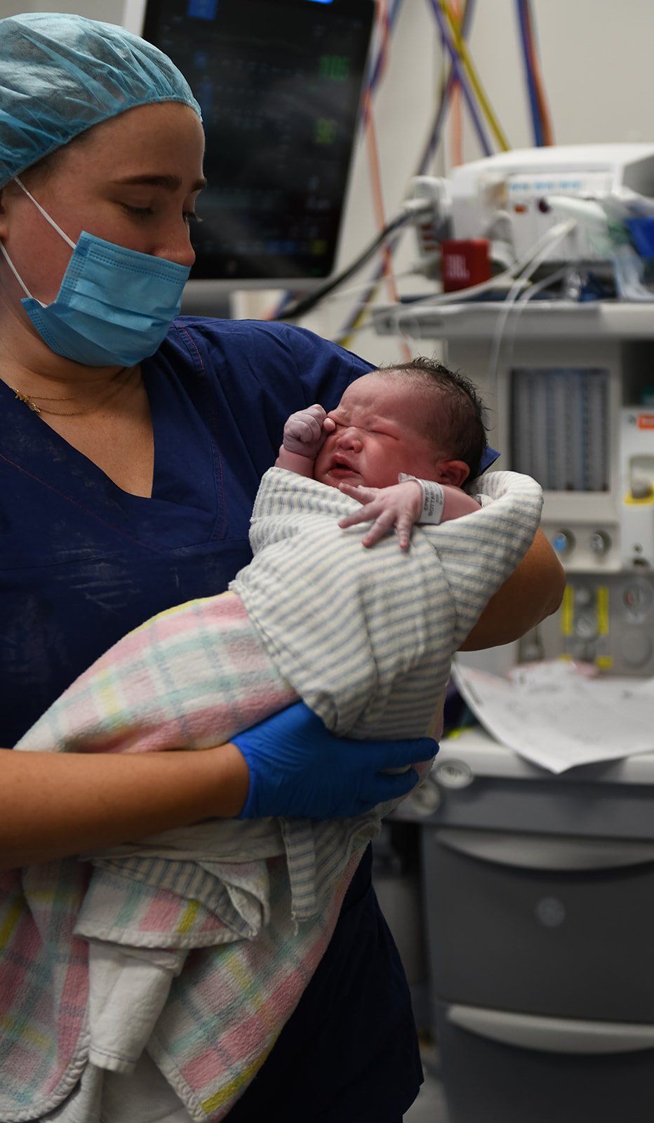 A midwife in scrubs holding a newborn in the birth suite