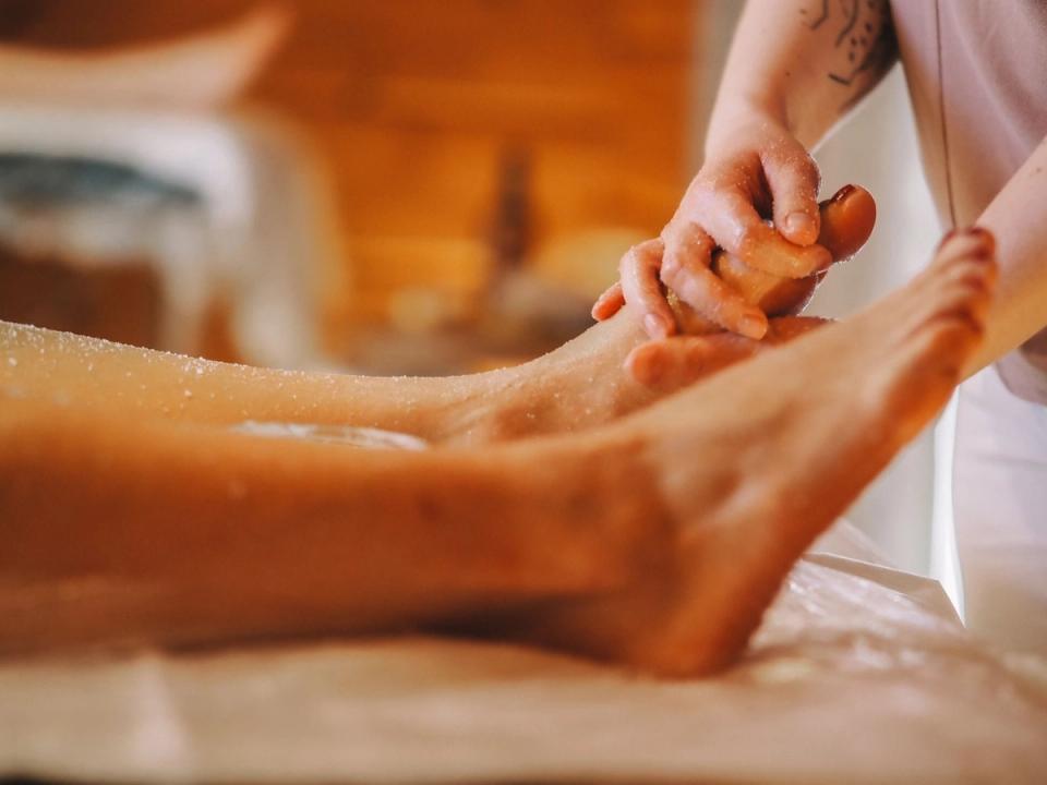 A therapist's hands massage a salt scrub into a client's foot during a foot ritual