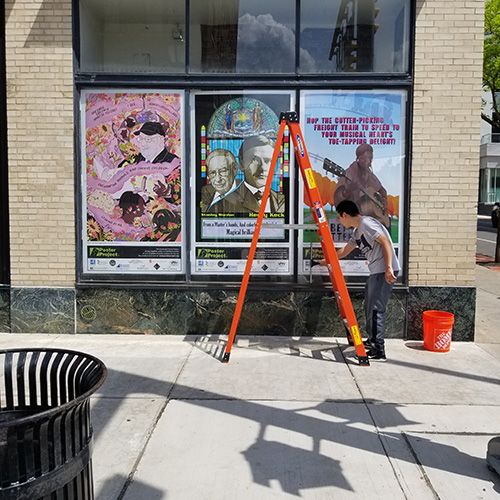 Jianghui Li installing poster panels at Landmark Theatre