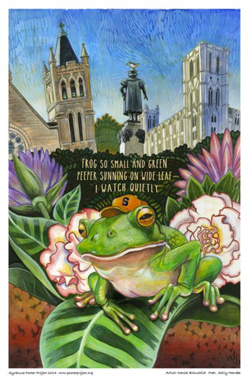 A frog sits on a leaf and wears an orange Syracuse hat with the statue in Syracuse's Columbus Circle visible in the background