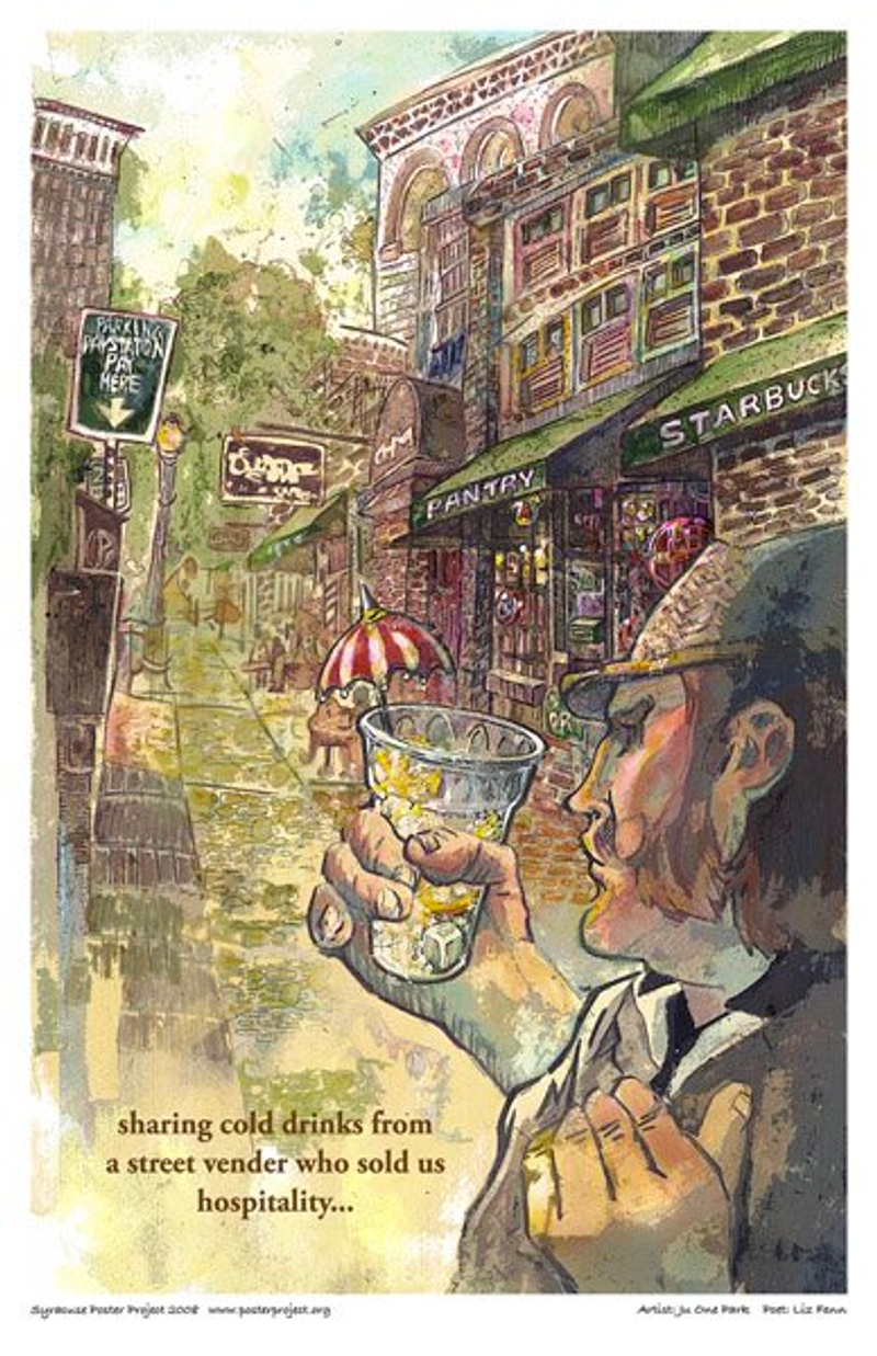 A man holds an icy drink on a street filled with shops and red brick buildings