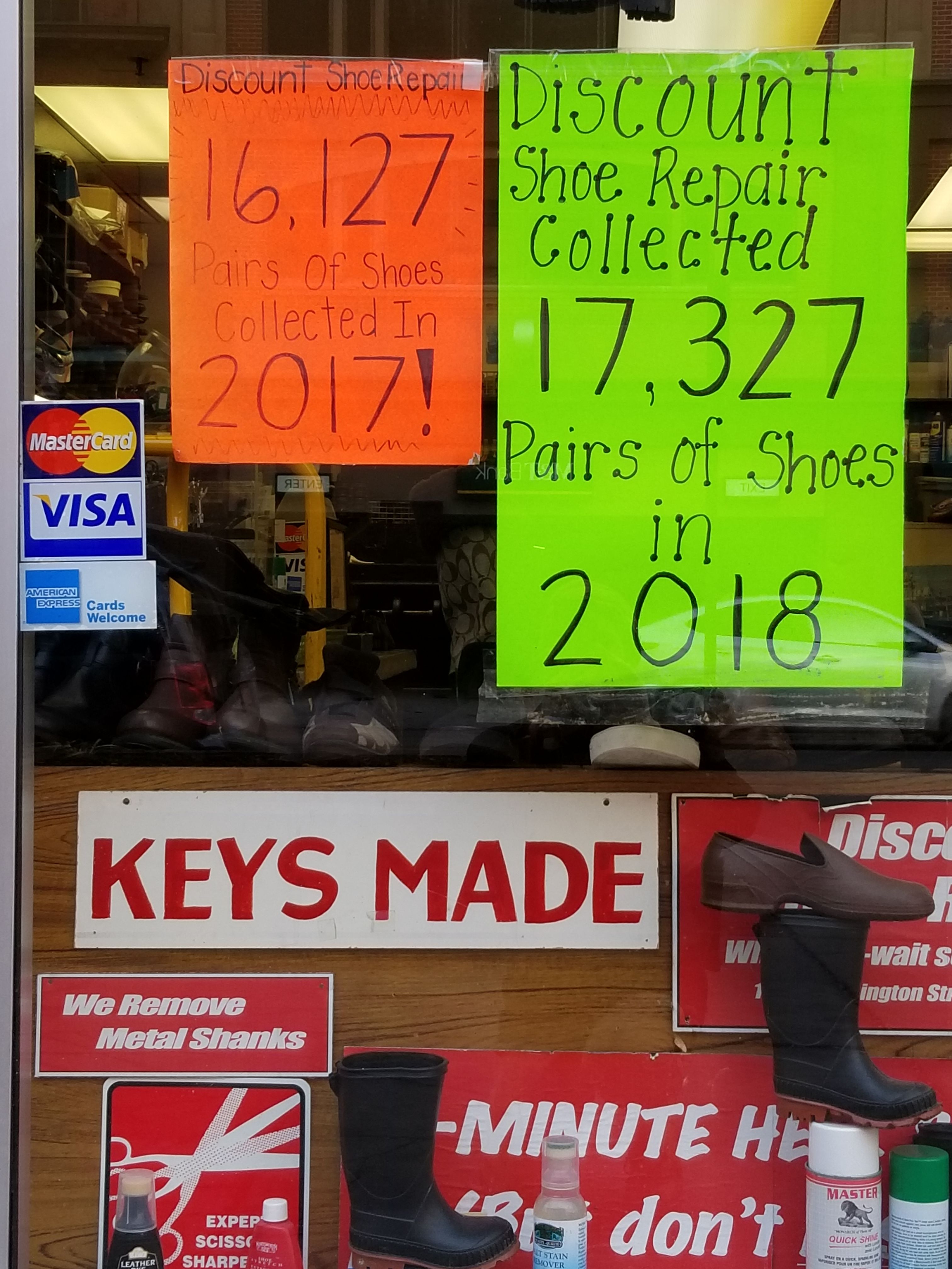 Discount Shoe Repair store window with signs about shoe collection