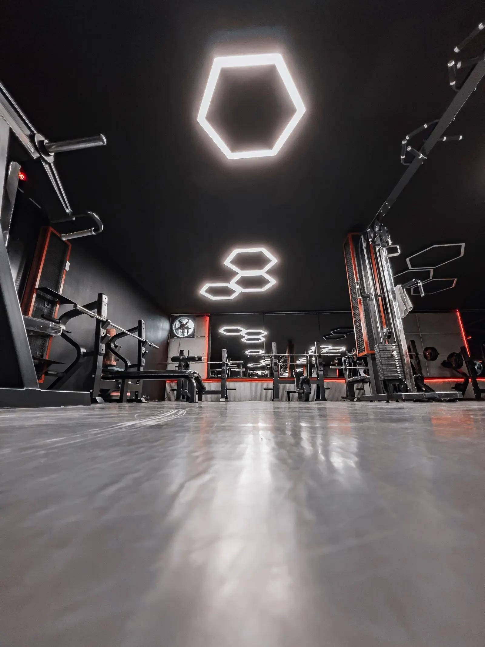 Interior gym dengan pencahayaan geometris dan alat kebugaran
