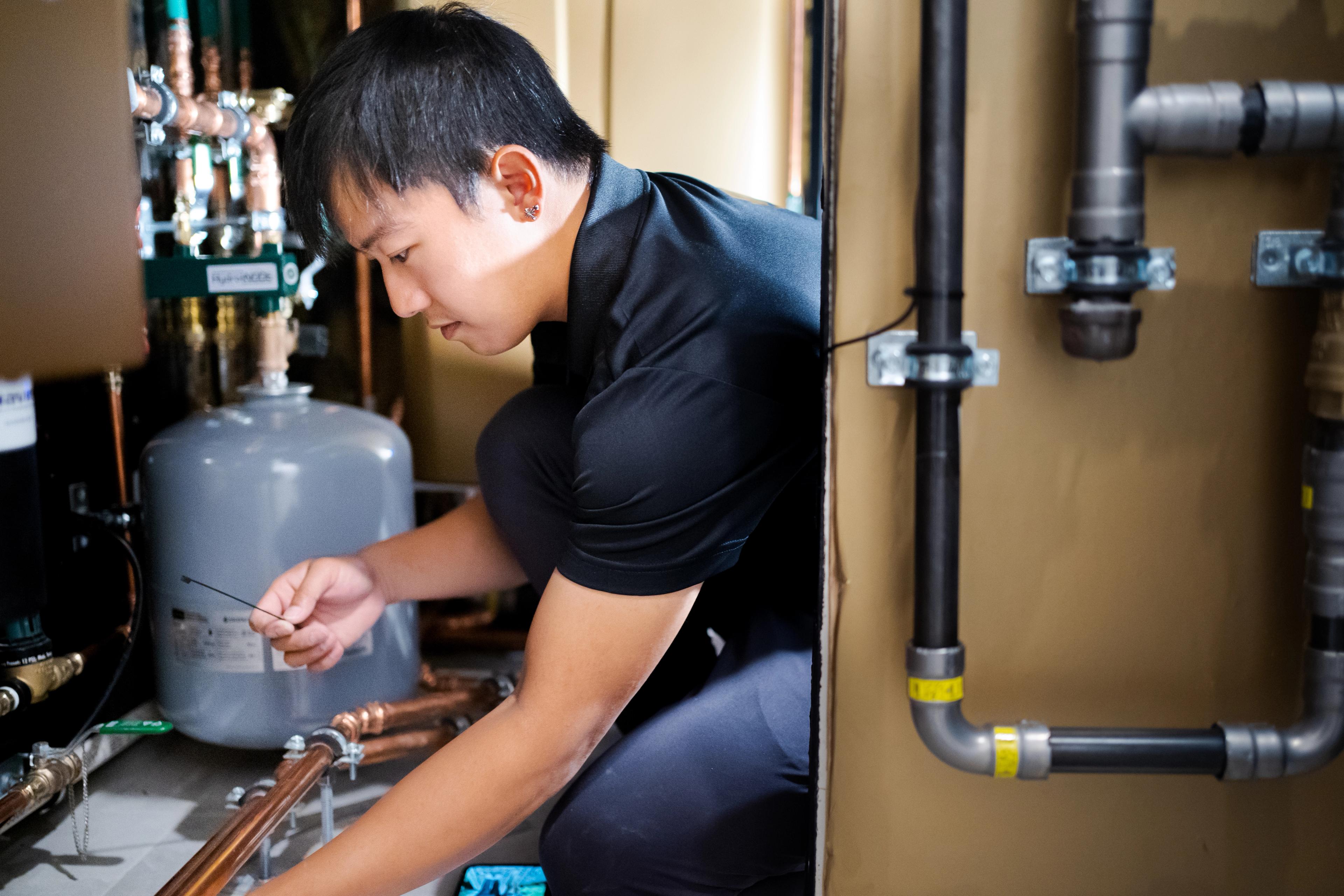 A man kneeling and inspecting plumbing