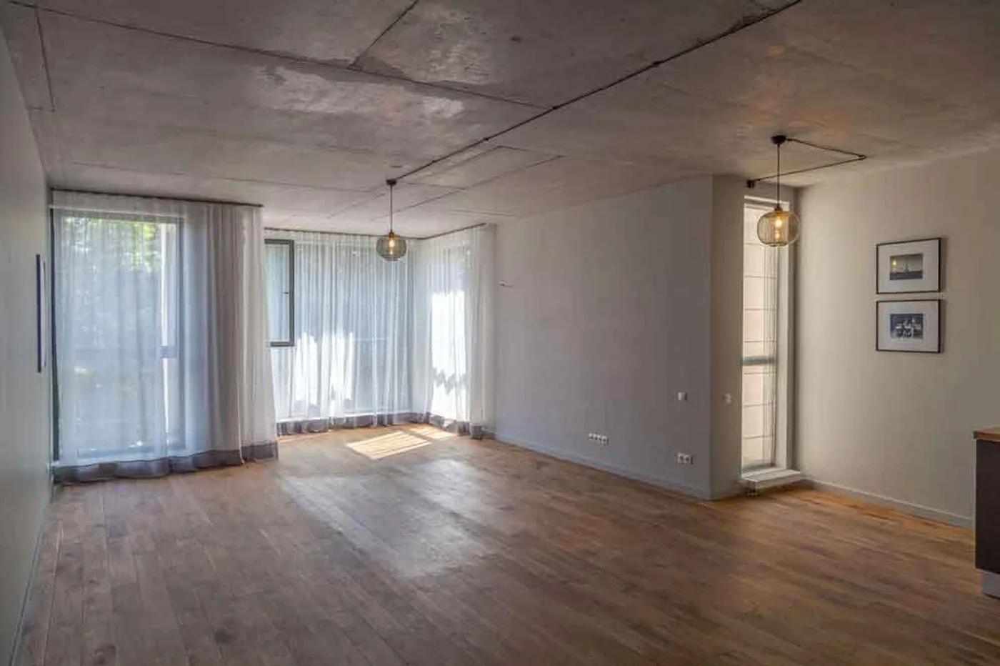 Bright loft living room with an exposed concrete ceiling and floor-to-ceiling curtains