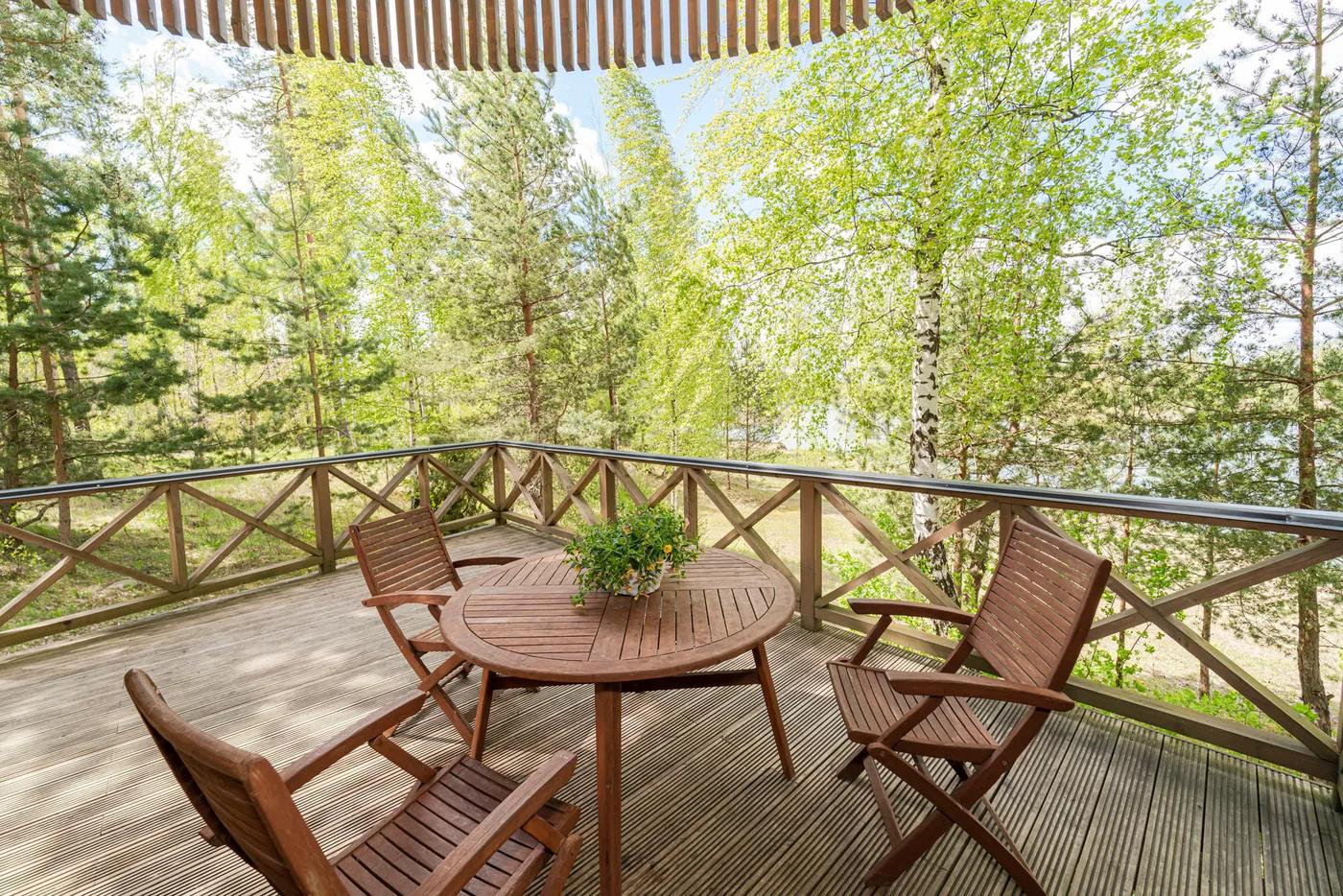 Round wooden terrace with outdoor dining table surrounded by forest