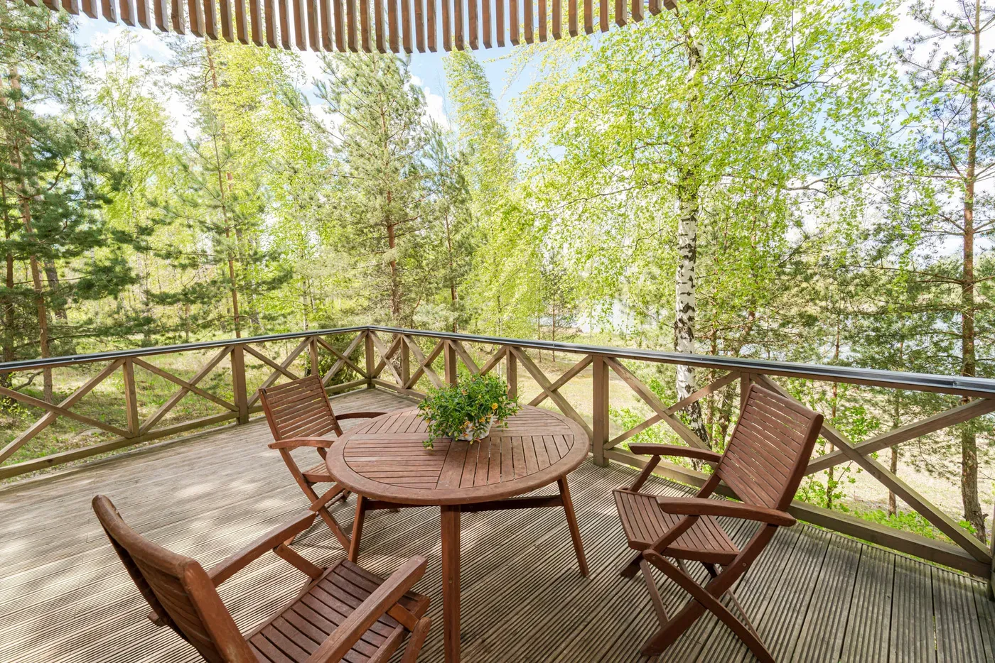 Round wooden terrace with outdoor dining table surrounded by forest