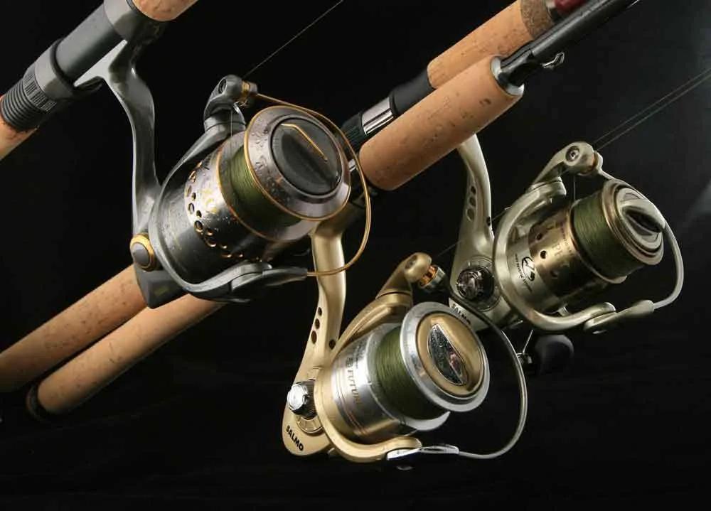 Close-up of fishing reels mounted on rods against a black background