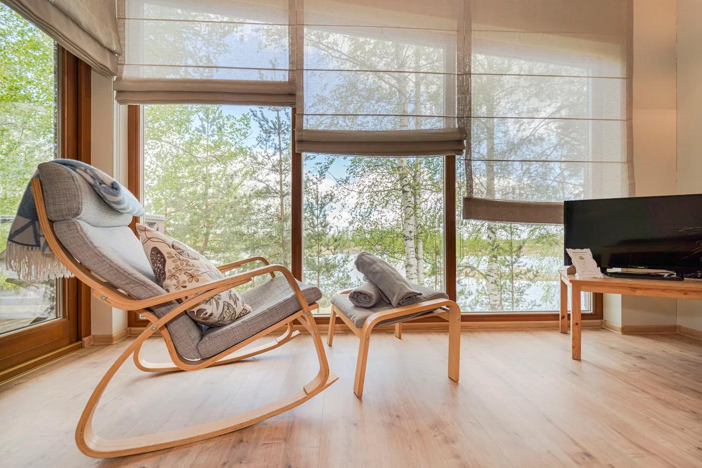 Cozy armchair and footstool by a floor-to-ceiling window overlooking a lake