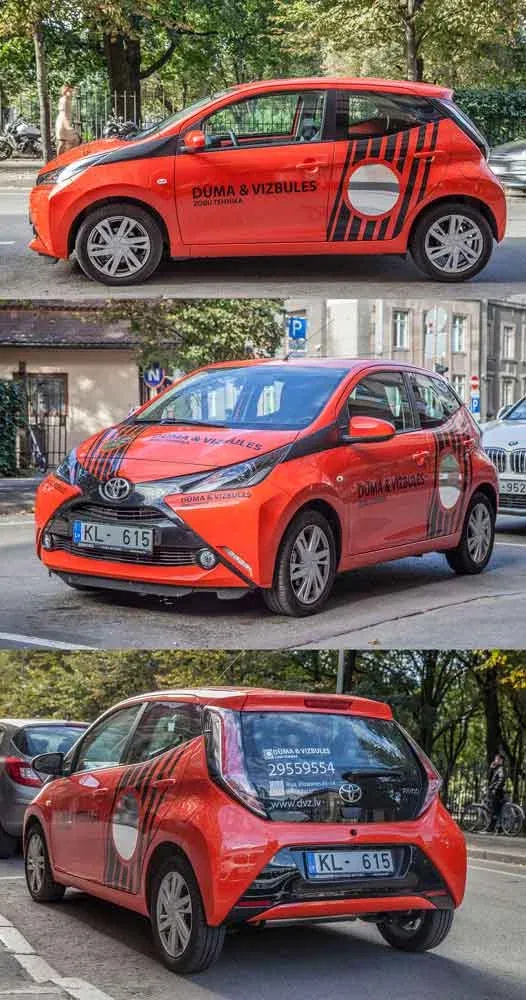 Oranžs un melns Toyota aplīmējums Dūma un Vizbules zīmolam, fotografēts no trim leņķiem pilsētas ielā