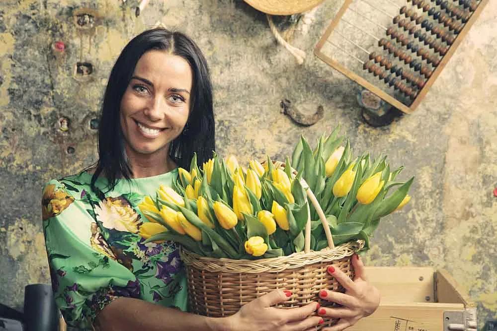 Woman holding a basket of yellow tulips in a rustic setting