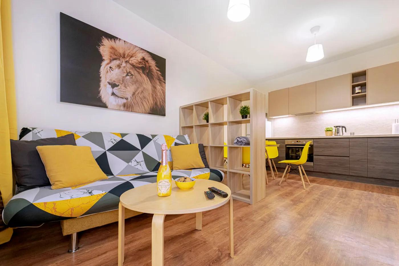 Studio apartment living room with a yellow and grey geometric sofa and open kitchen