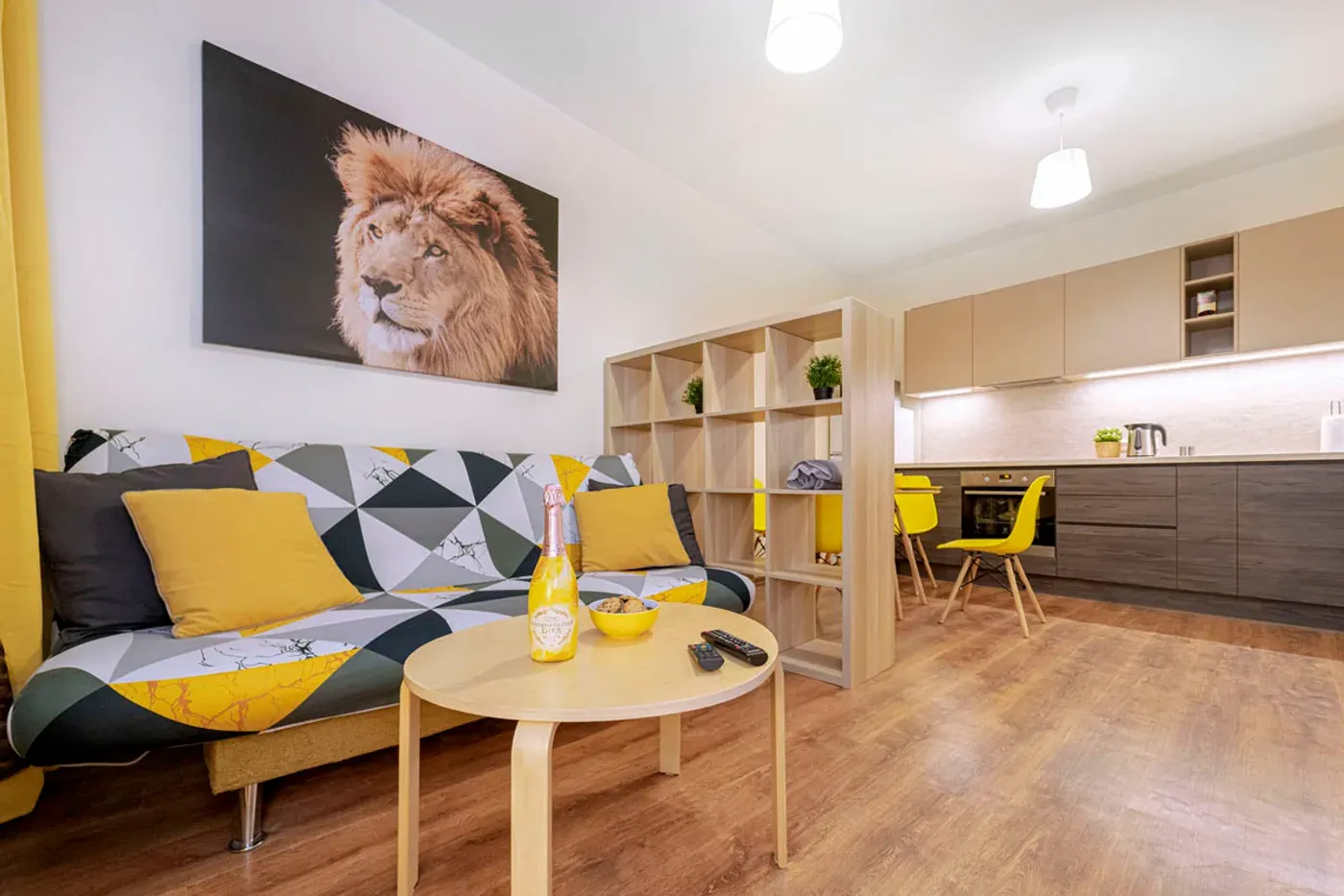 Studio apartment living room with a yellow and grey geometric sofa and open kitchen