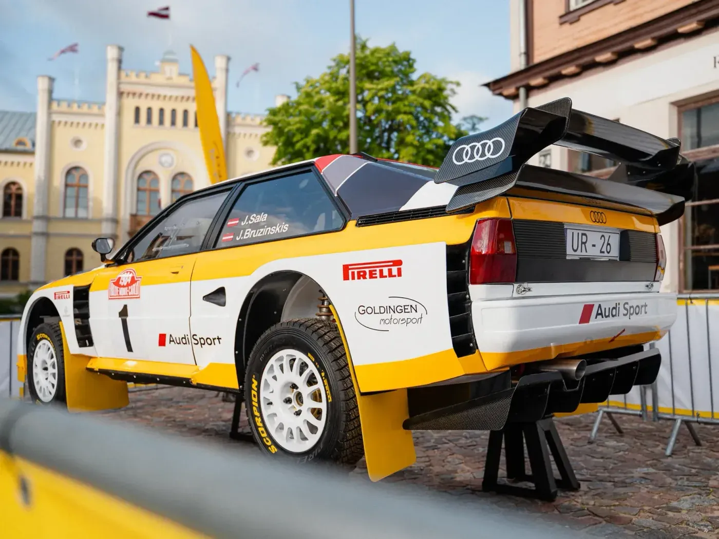 Original photo of the rear of the Audi rally car outdoors in front of a historic building