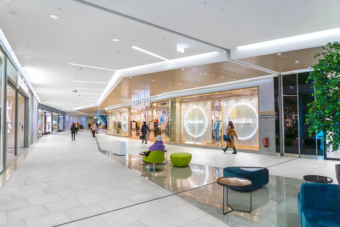Bright commercial interior of a shopping mall corridor with storefronts
