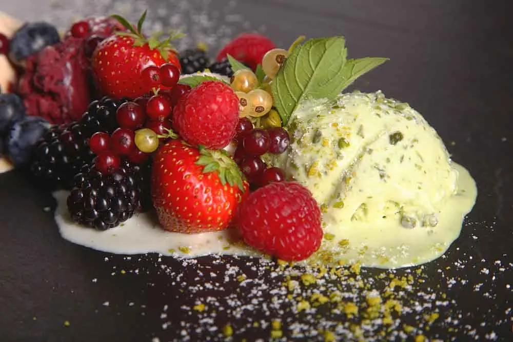 Fresh berries with pistachio ice cream and cream on a slate plate