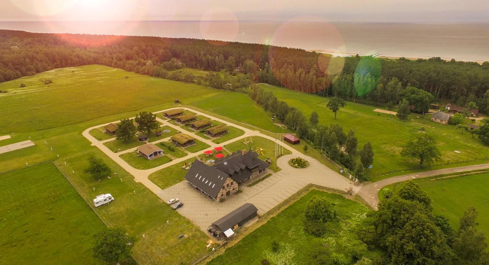 Aerial drone photo of a countryside resort property near the sea at sunset