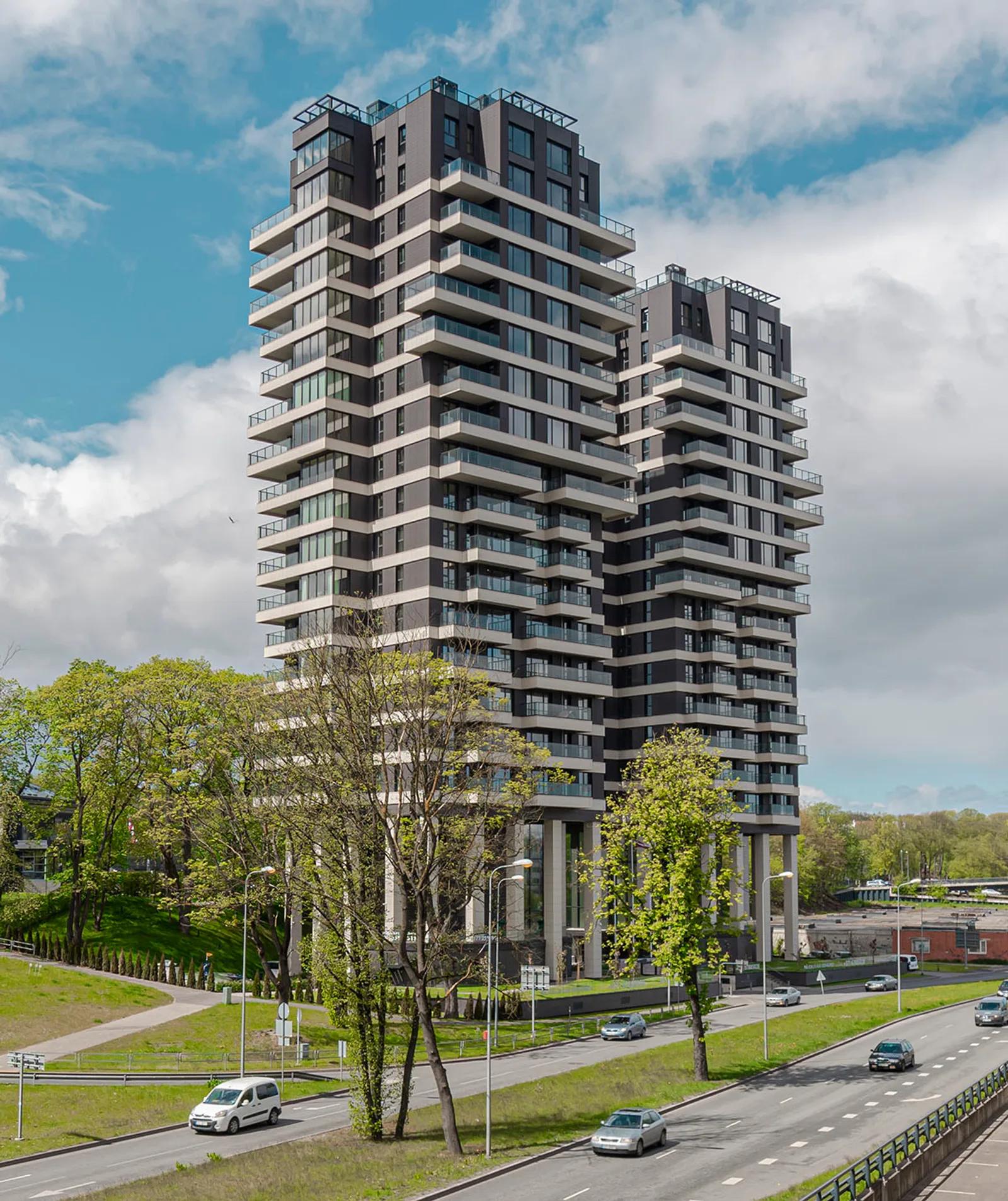 Exterior photo of a modern high-rise residential tower with balconies, photographed from the street