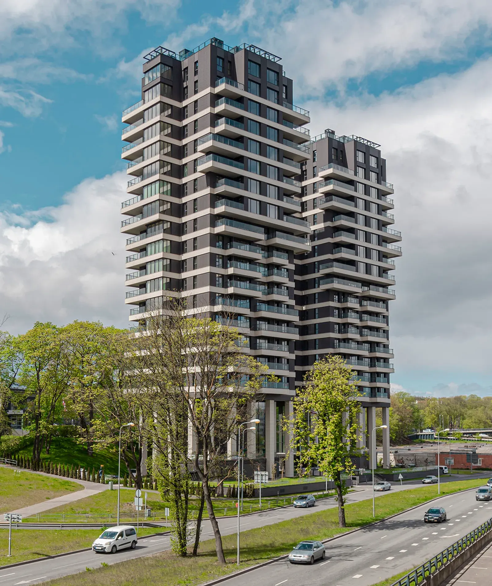 Exterior photo of a modern high-rise residential tower with balconies, photographed from the street