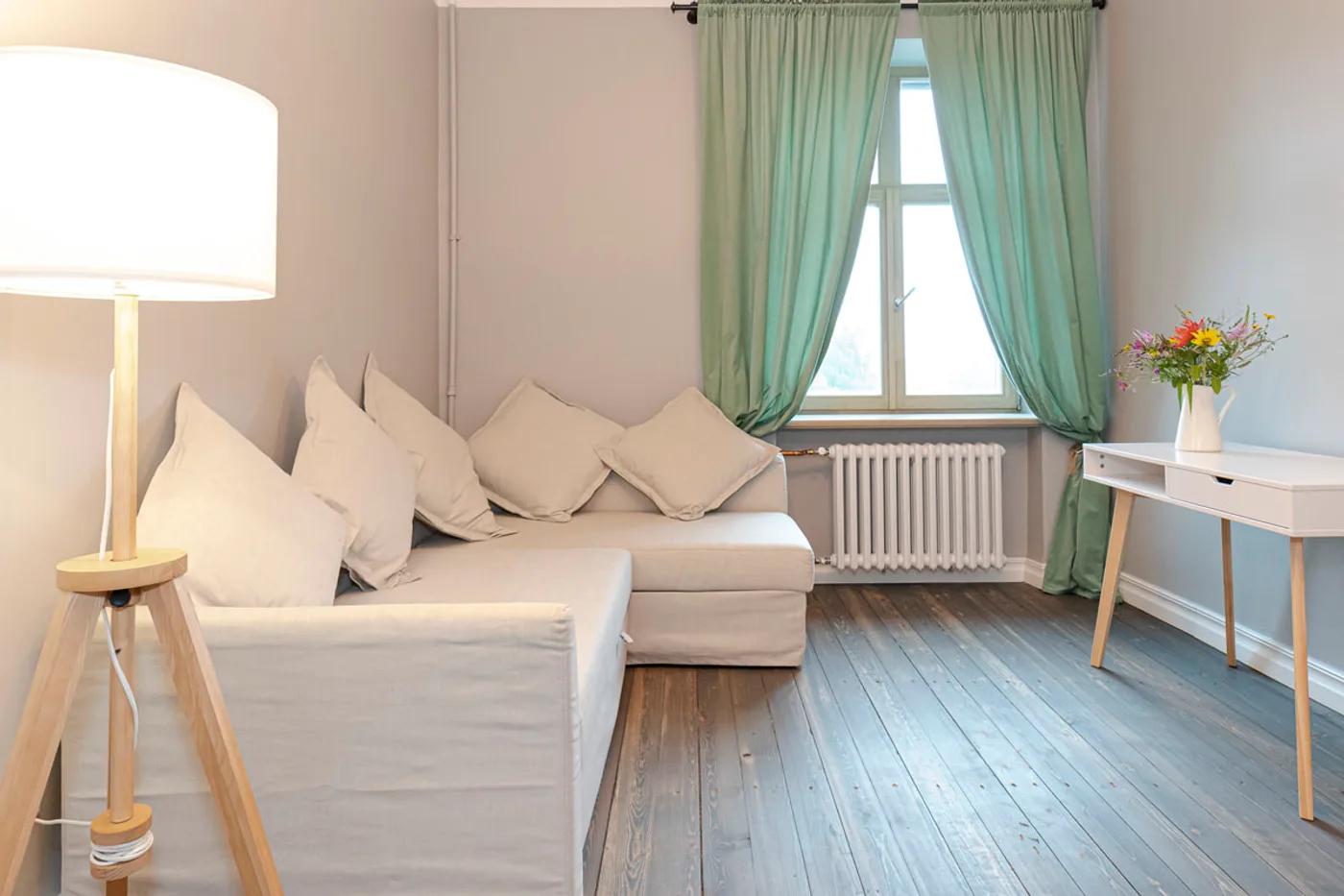 Cozy living room with a beige sofa, sage green curtains and wood flooring