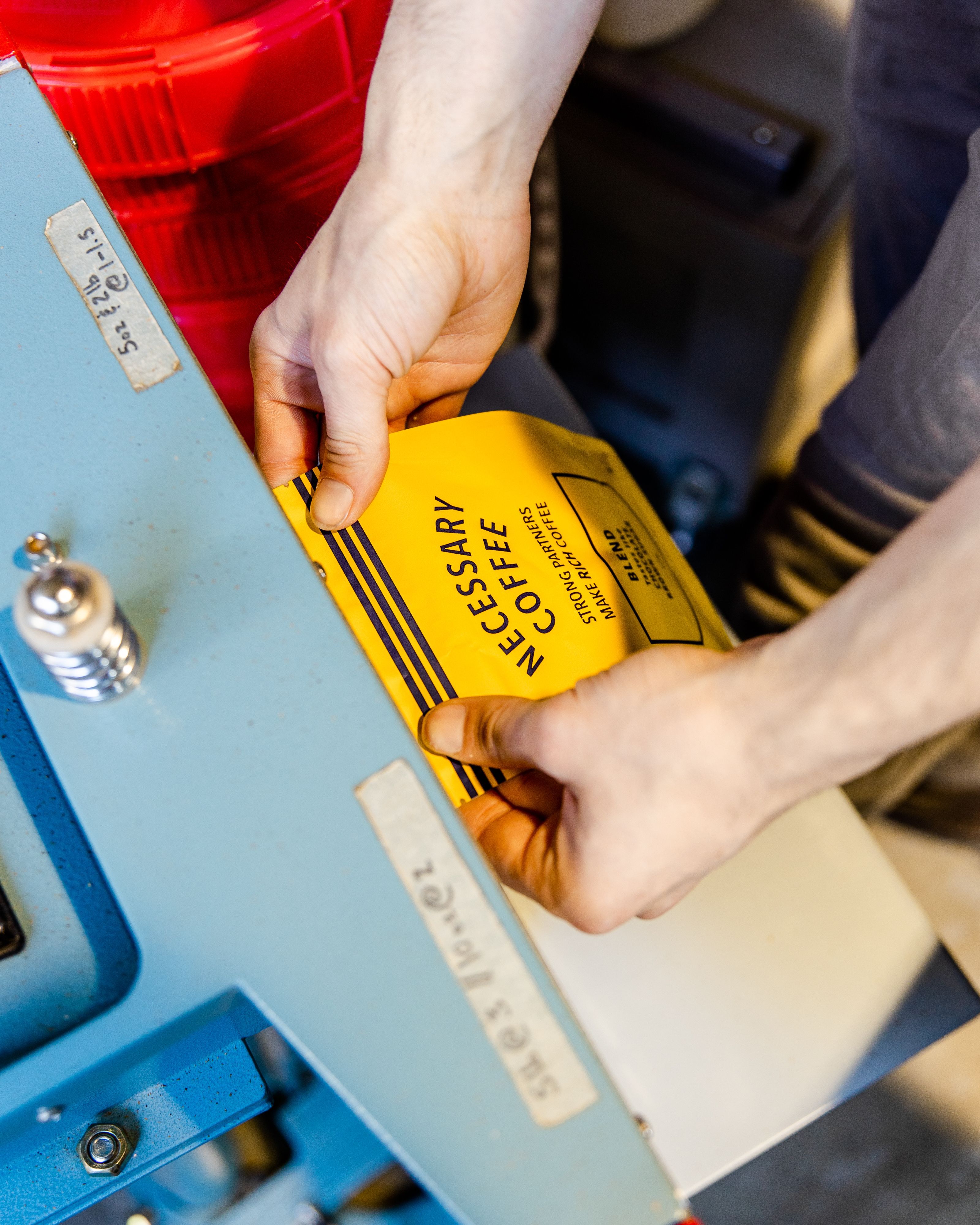 A Necessary Coffee bag being sealed for quality at the Passenger Roastery