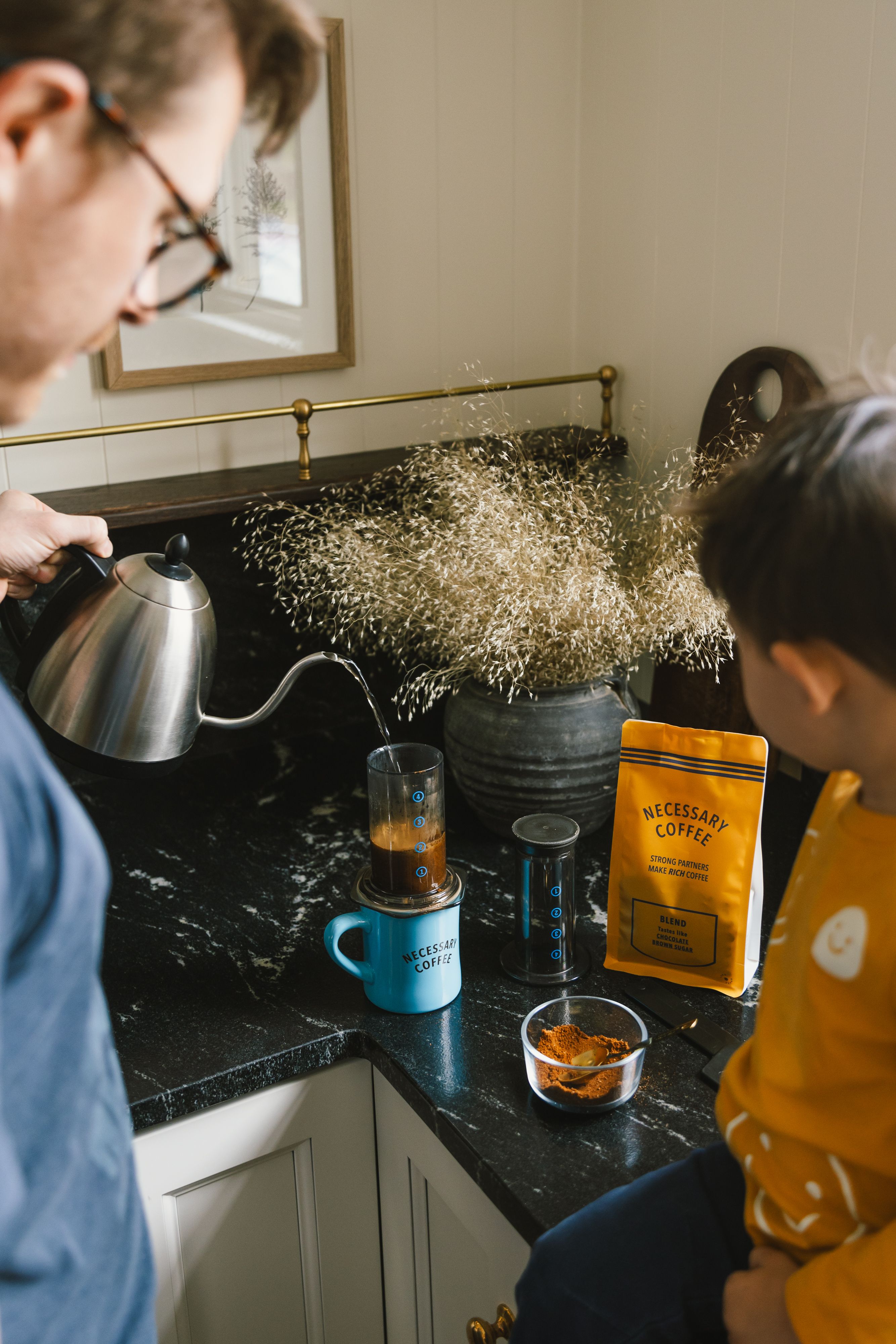 A father and son brew coffee in an aeropress at home