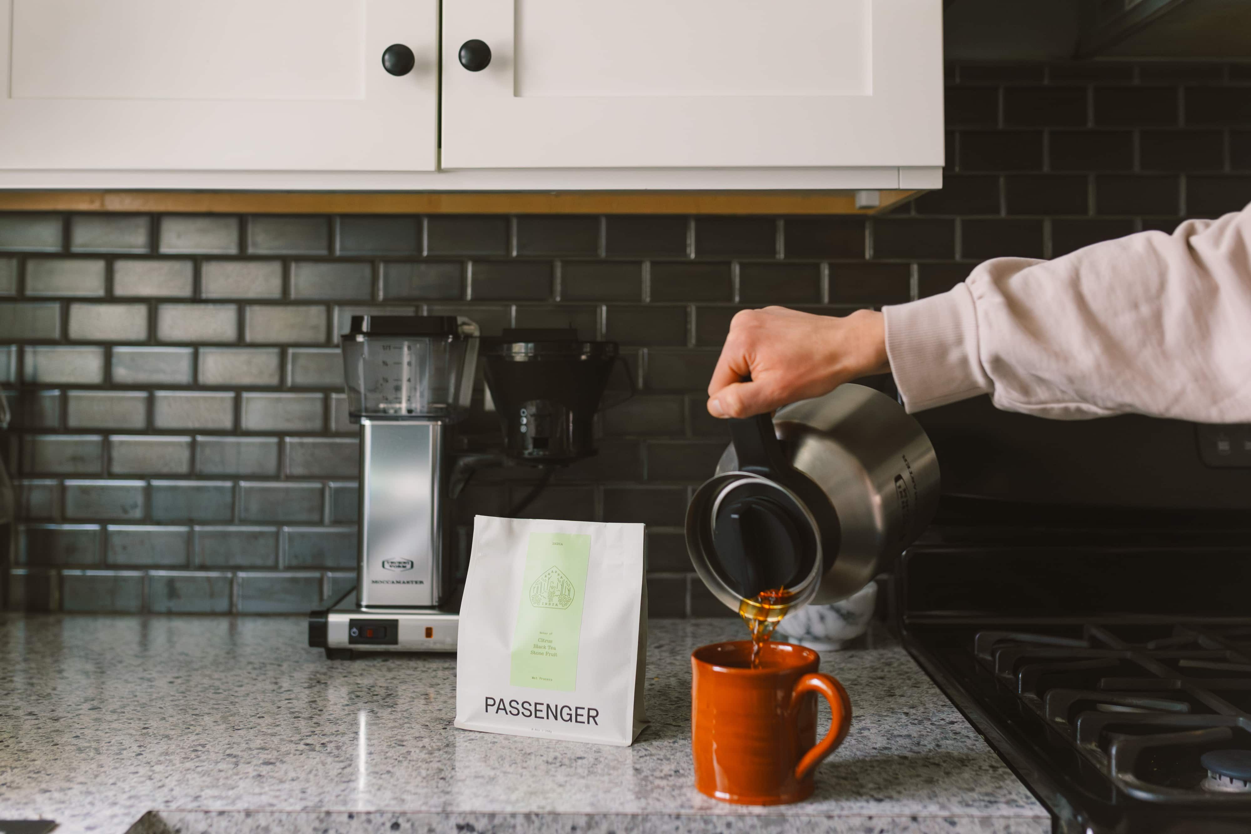 A person pours a cup of coffee in the kitchen