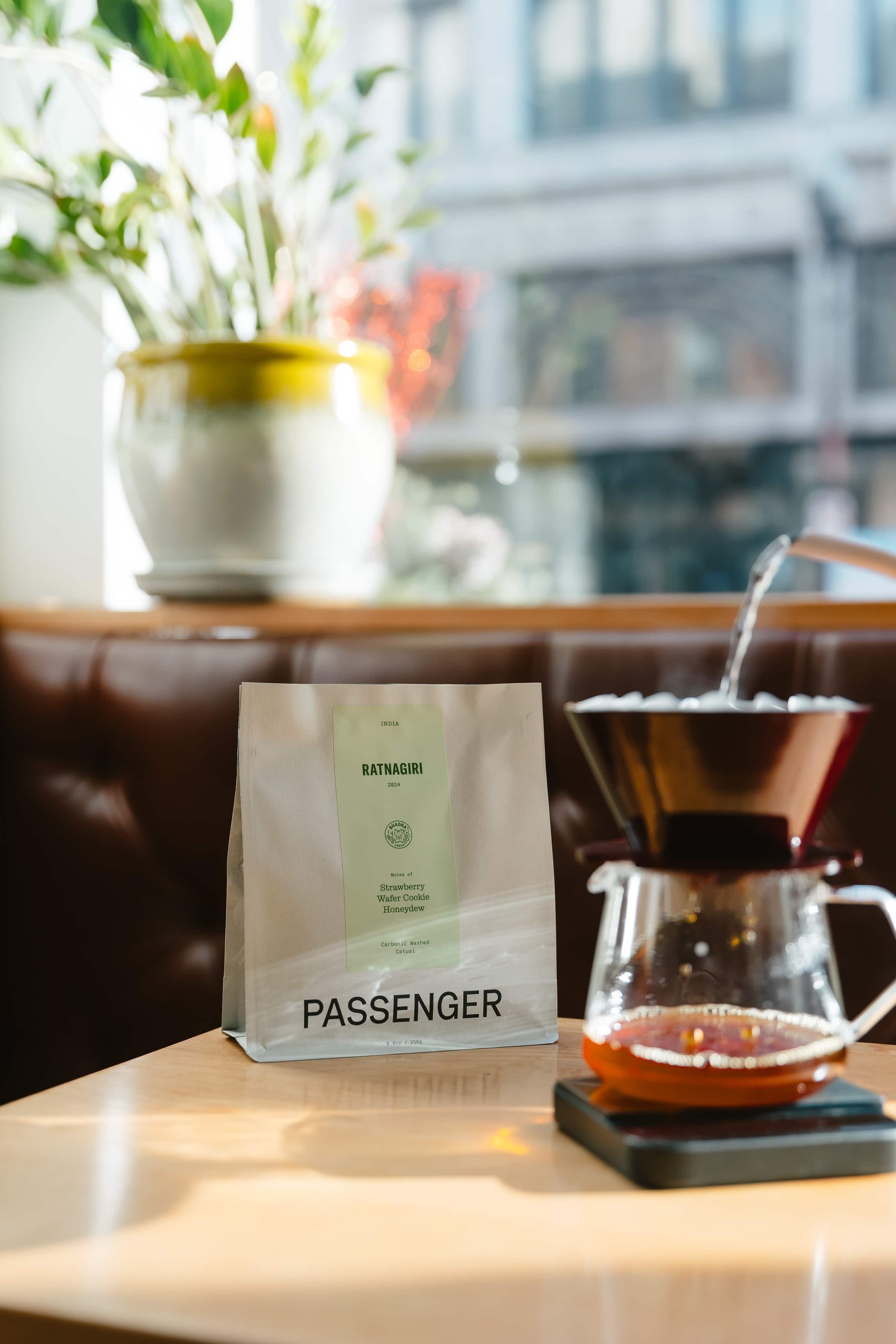 A bag of coffee sits next to a pour over of coffee