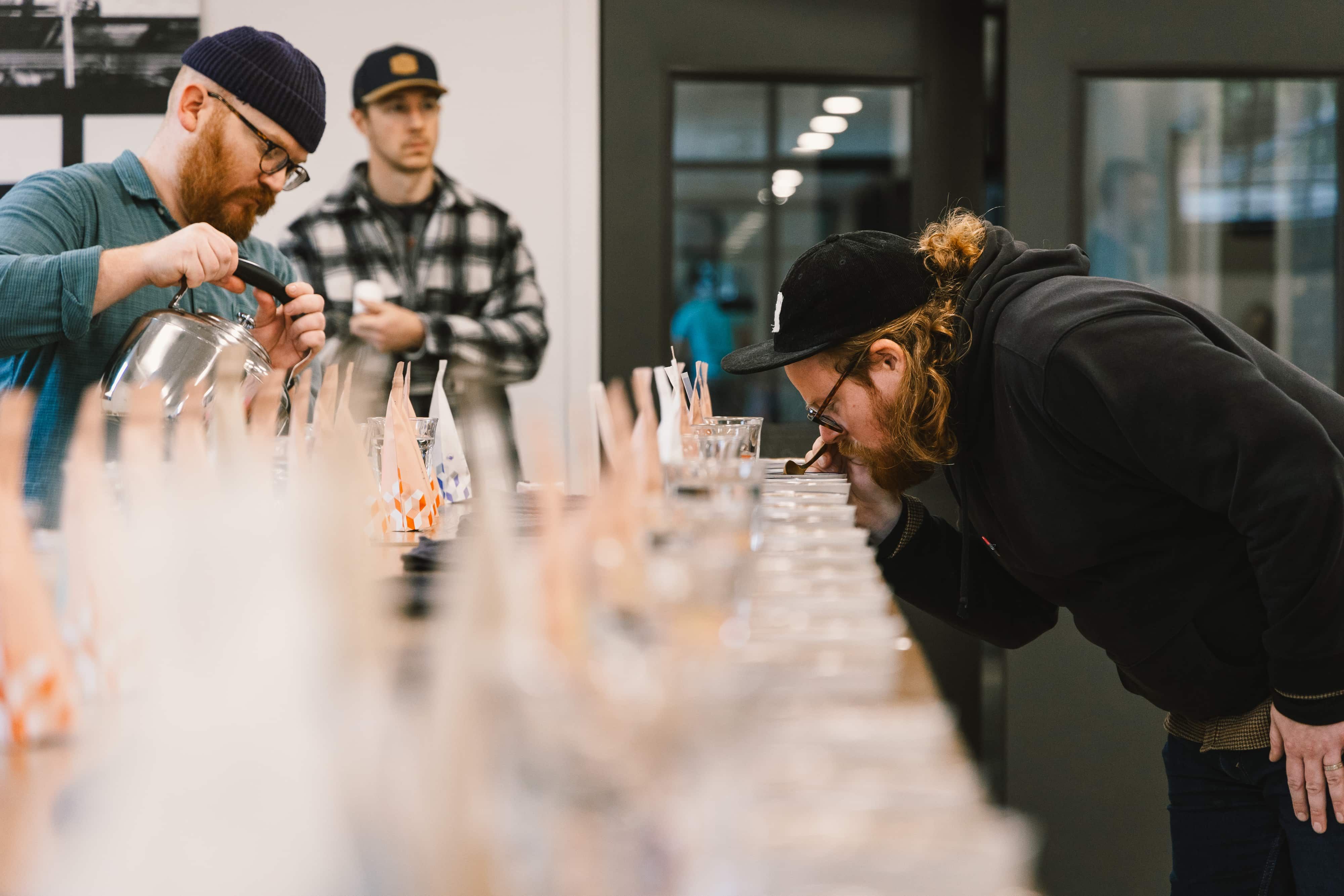 Two men slurp coffee during a coffee cupping