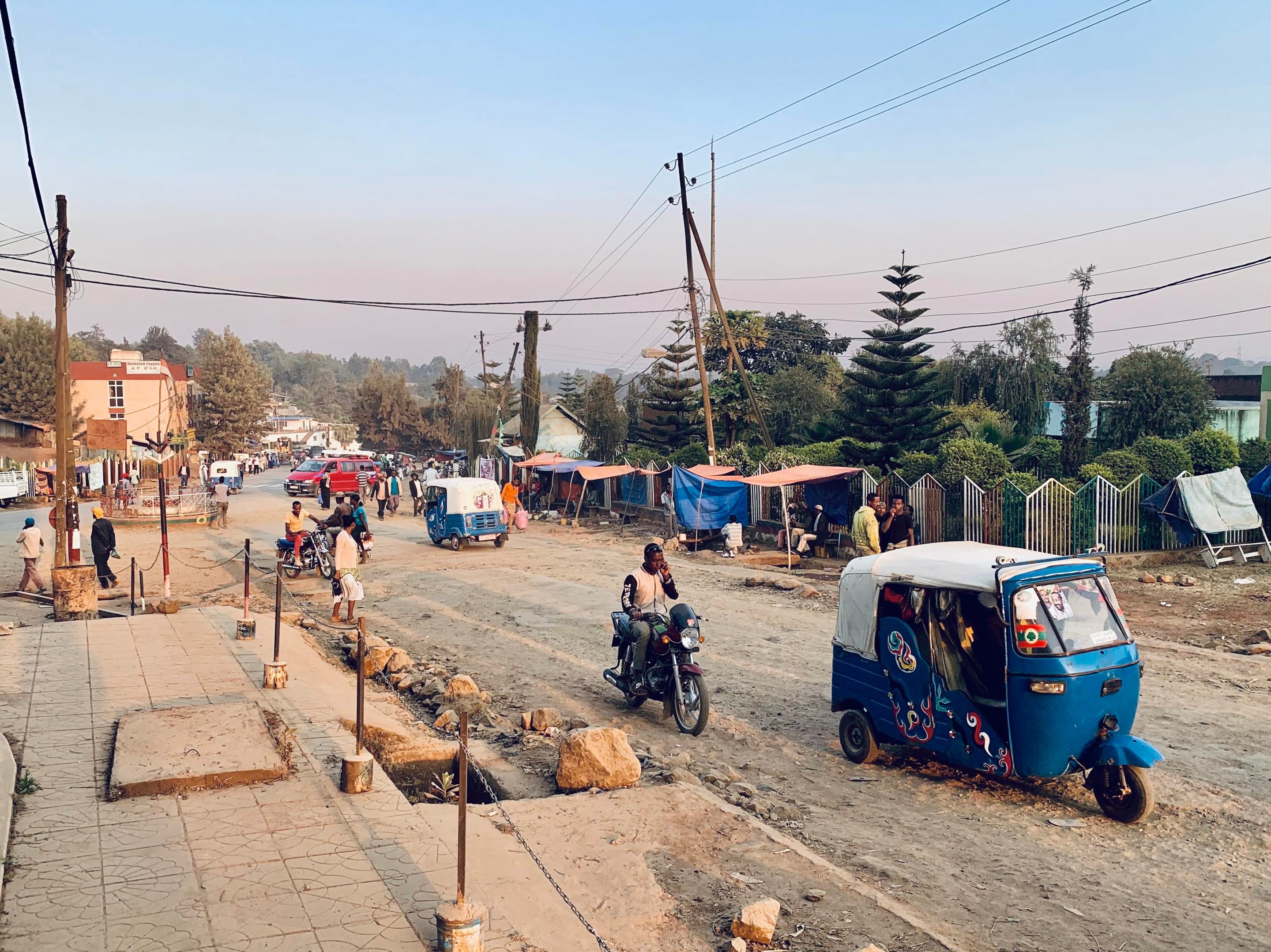 A dirt road in Ethiopia with motorbikes and small cars