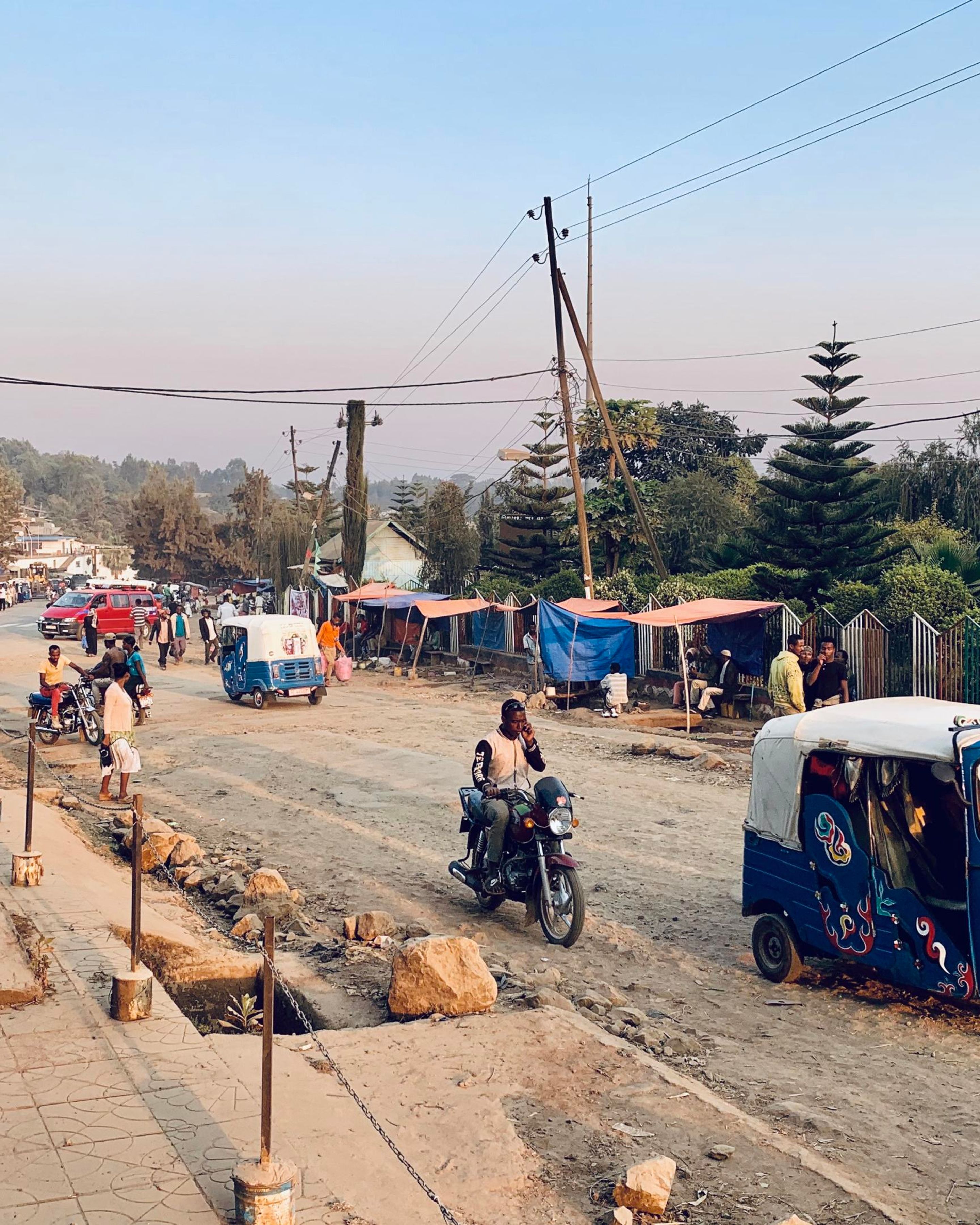A dirt road in Ethiopia with motorbikes and small cars
