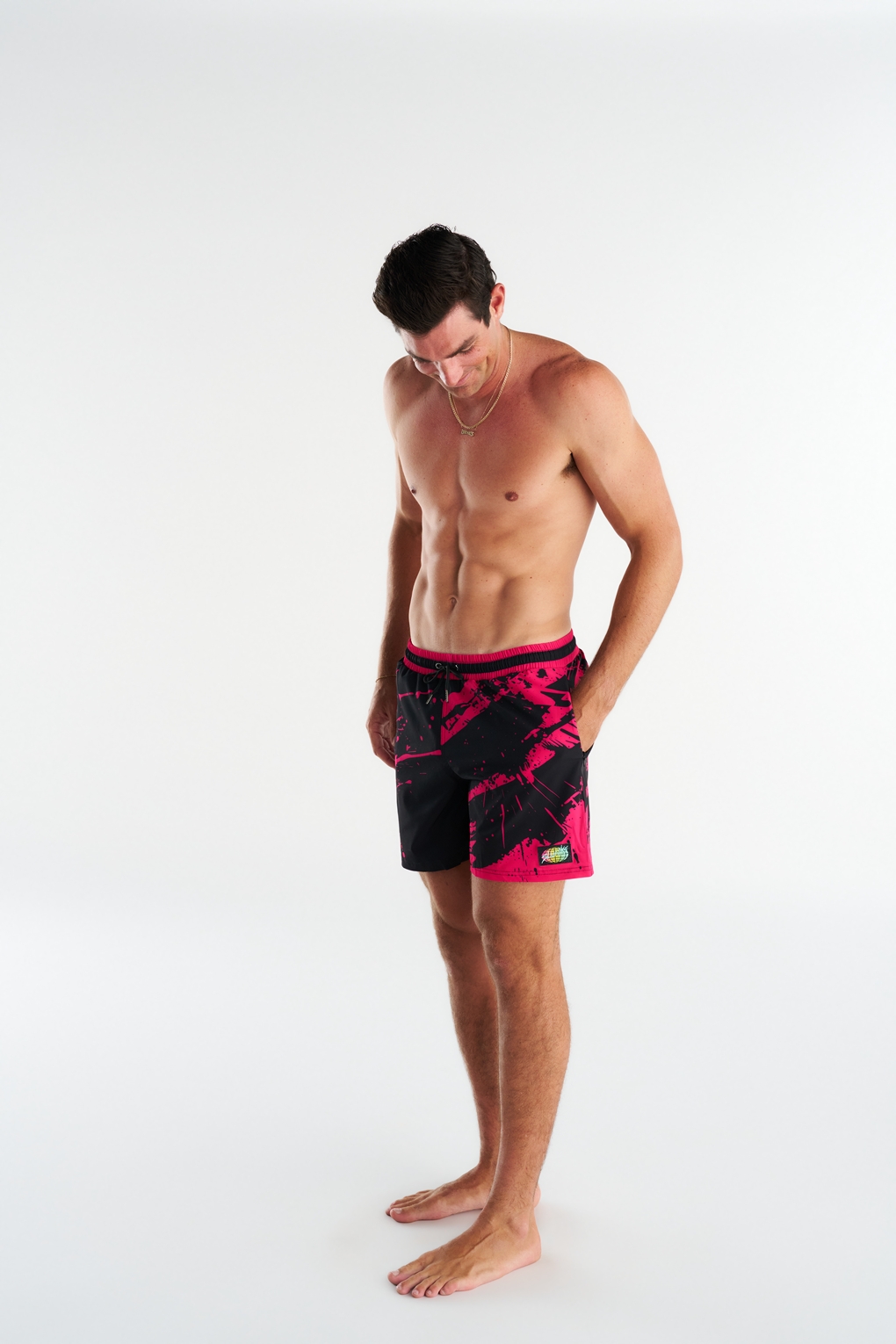 Side View- Troy Field wearing his custom Slunks boardshorts, black shorts with pink abstract graphics