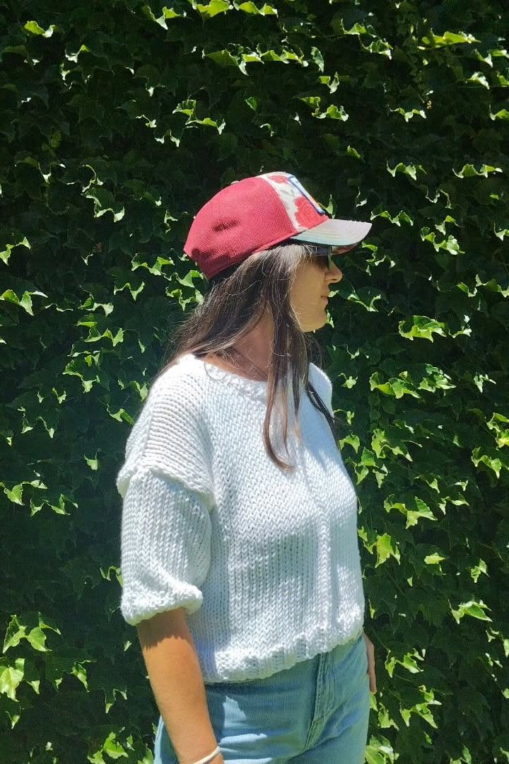 Mujer posando en un patio con un suéter tejido a mano de Nido Trama