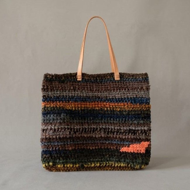 Bolso tejido a mano de Nido Trama en primer plano, presentado sobre superficie minimalista estilo museo