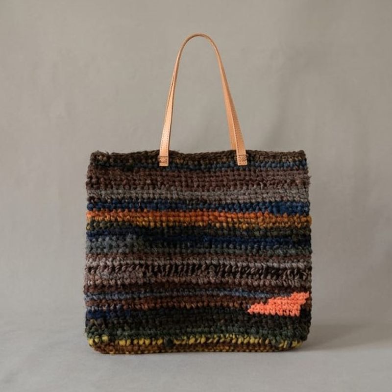 Bolso tejido a mano de Nido Trama en primer plano, presentado sobre superficie minimalista estilo museo