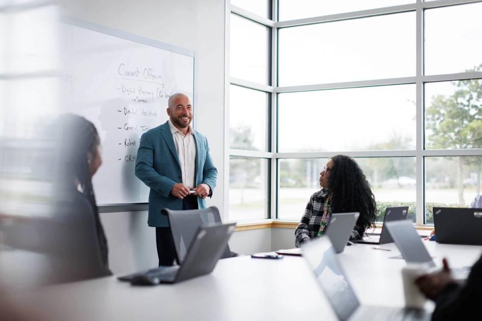 Presenter leading business meeting by whiteboard in bright conference room