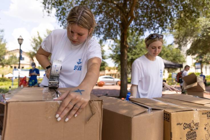 Two Rollins student volunteers packing boxes for the community. 