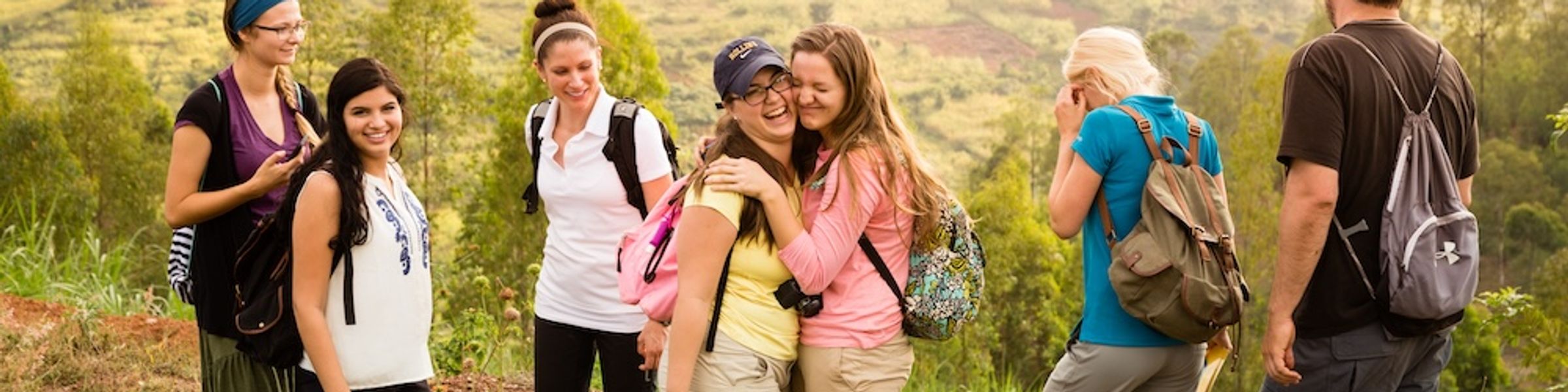 A group of Rollins students gather to pose while walking in a field in Rwanda.