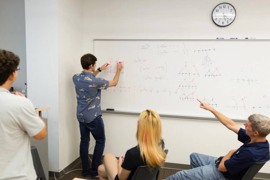 A Rollins student completes a math equation on a white board.