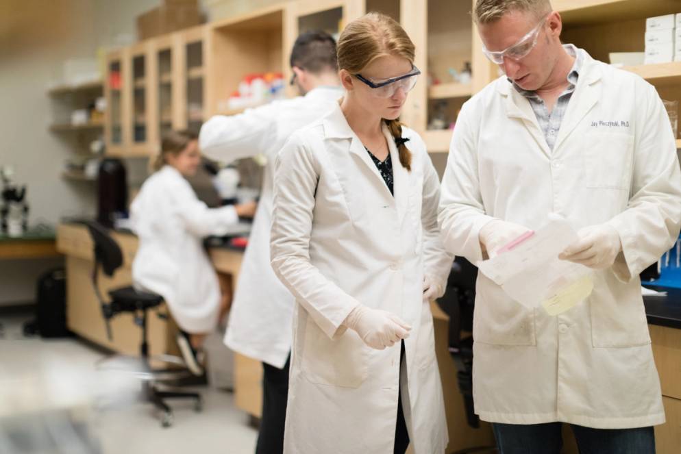 A biology student speaks with a professor during a lab.