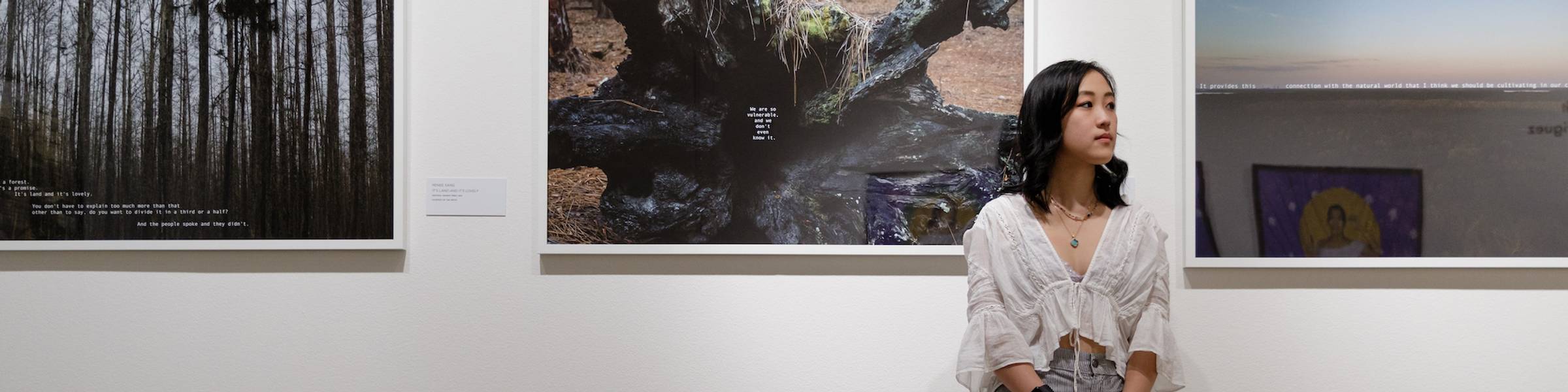 A Rollins student stands with art at a gallery.